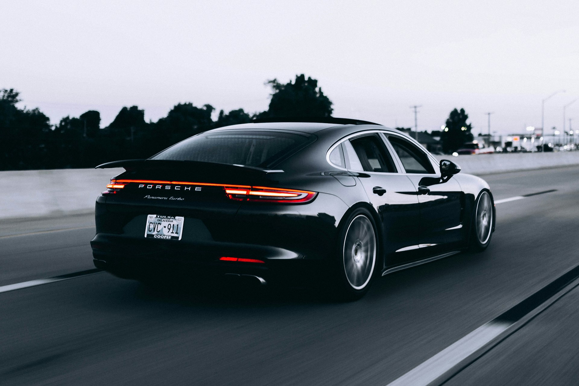 A dark sports car photographed from behind on a road
